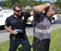Un policía simulando una detención con una réplica de pistola de goma