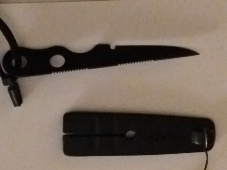 Color negro, unos 12 cms. de largo y 5 de hoja, hoja de acero, con funda de polímero y cordón de seguridad.

Sin 00
